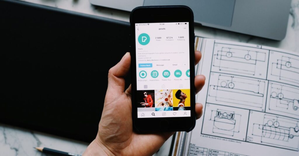 Widok konta na Instagramie na telefonie z planami projektowymi w tle